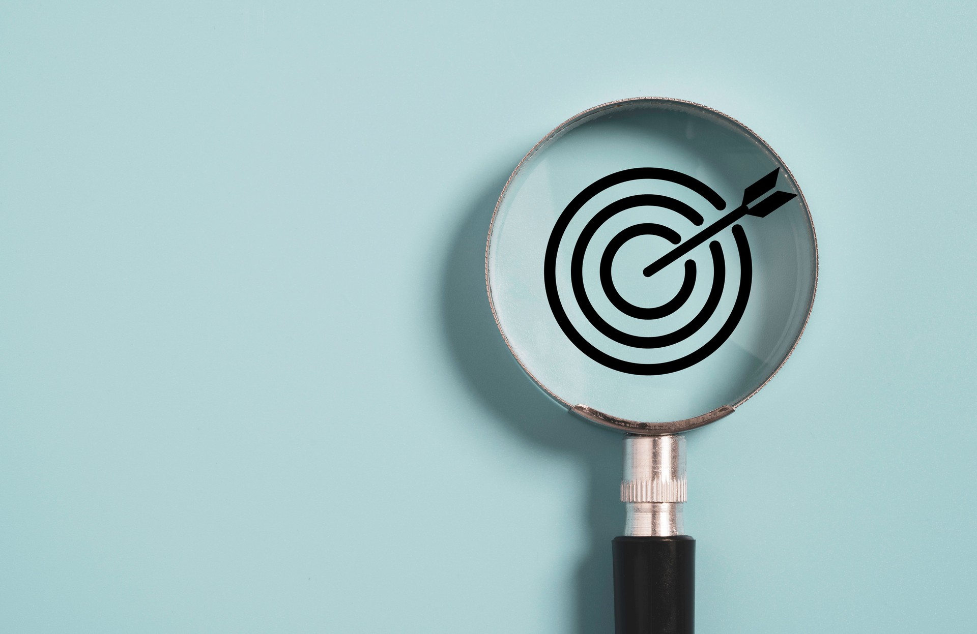 Target board inside of magnifier glass for focus business objective on blue background and copy space.
